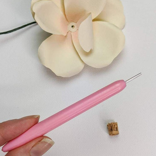 Pink quilling tool with a rolled up center strip and an ivory paper rose.
