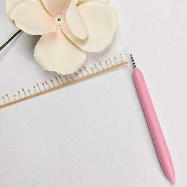 Pink quilling tool with a paper flower center strip and ivory paper rose.