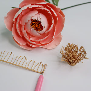 Quilling tool rolling up a paper flower center with a pink paper peony and a completed paper peony center.