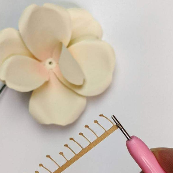 Quilling tool rolling up a paper flower center for an ivory paper rose.